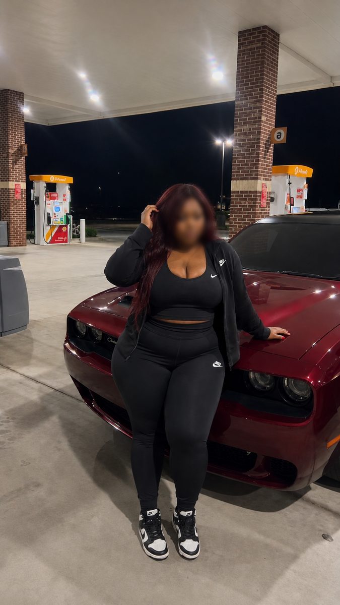 Samantha in black athletic wear leaning on a burgundy car