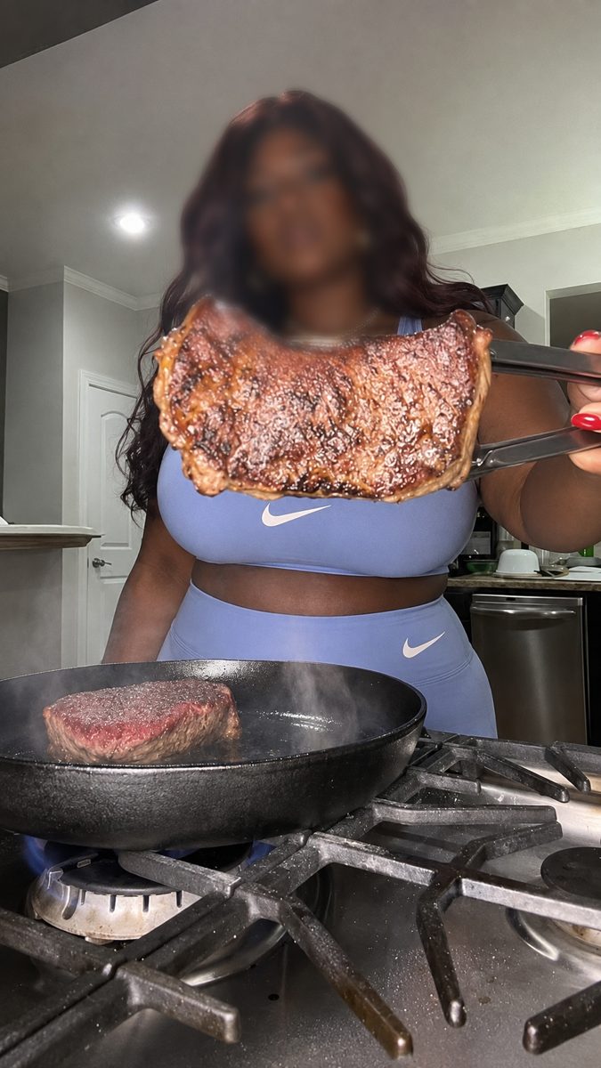 Samantha in a blue athletic set holding up a seared steak over a cast iron pan